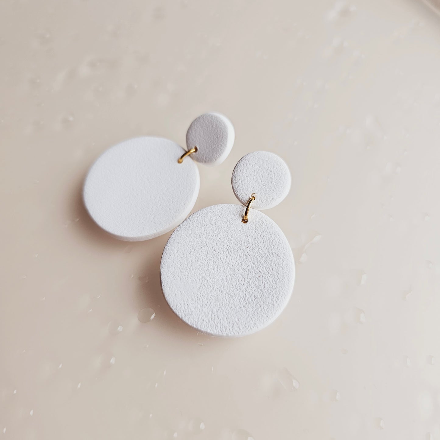 White circle earrings by evelet designs. They have a concrete textured look. 